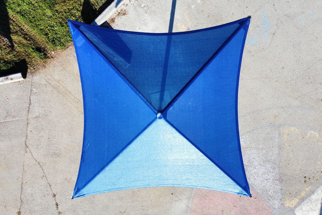 Bird's-eye view of a blue Single Post Umbrella over a concrete playground area.