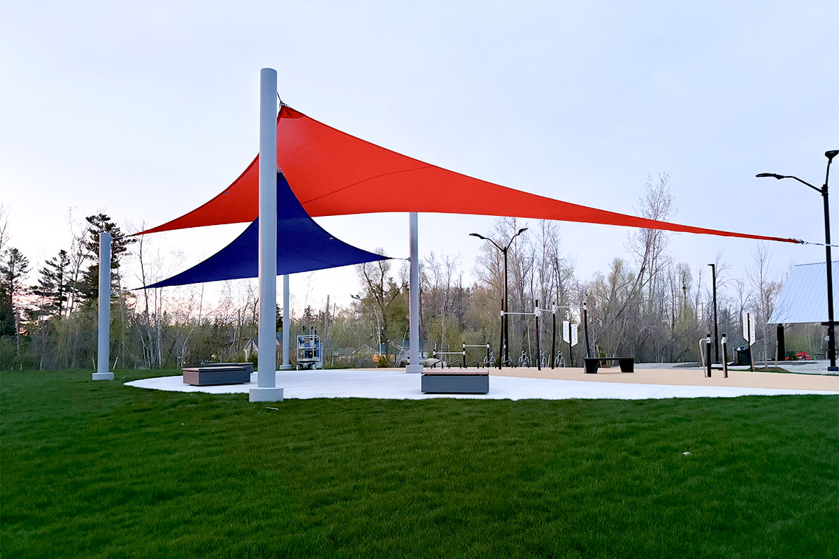 Professionally installed sloped shade sails providing shade and proper water drainage over a public outdoor space.